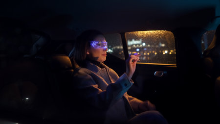 Portrait of an intelligent young woman sitting in the back of a car wearing virtual reality glassesの写真素材