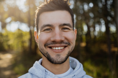 Portrait of young attractive man smiling into the camera in forestの写真素材