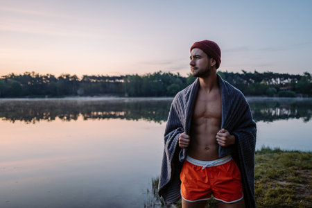 Serious guy at the forest near the water and preparing for the swimming in the cold lake at morningの写真素材