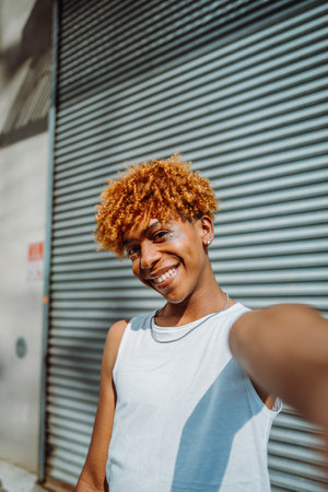 Vertical view of young millennial african american guy making selfie portraits on mobile phoneの写真素材
