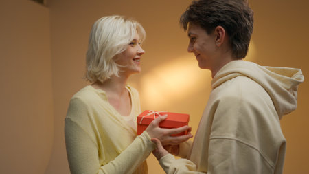 Happy man giving gift to his girlfriend on beige studio background, free space.の写真素材