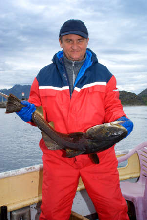 Fisherman with fish on the boat near the Lofoten island