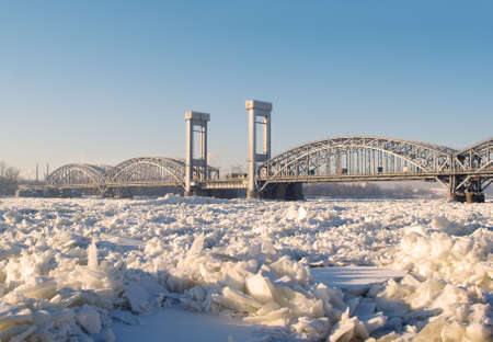 Railway bridge on the frozen river in sunny dayの写真素材