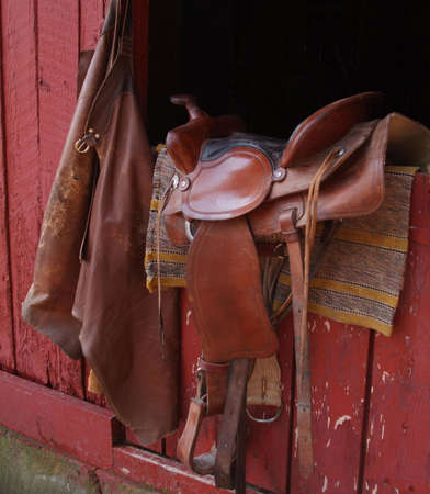 saddle and chaps on barn door with horse blanketの写真素材