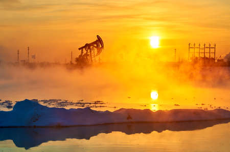The oil sucking machines in the vapour lakeside under sunrise.