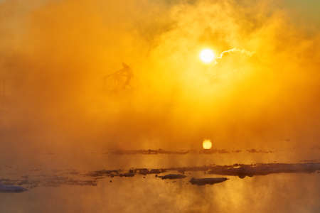 The oil sucking machines in the vapour lakeside under sunrise.の写真素材