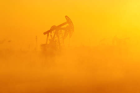 The oil sucking machines in the vapour lakeside under sunrise.の写真素材