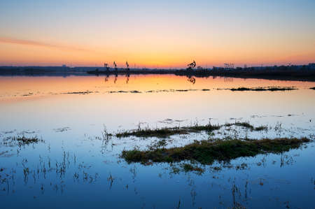 The oil fields by  lakeside with sunrise.