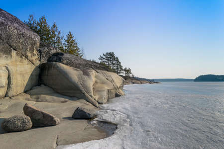 ice on frozen lake on a background of rocks and woodsの写真素材