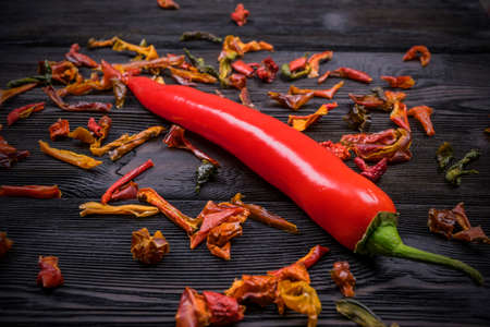 Red chili pepper on the dark wood texture background with spices, close up