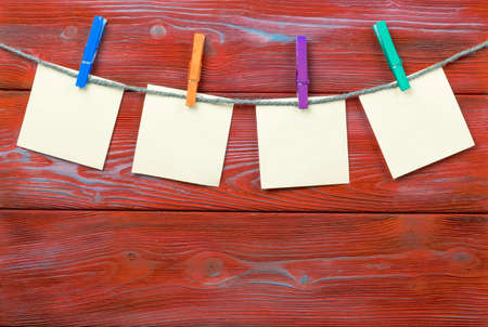 Clothespin hanging with blank photo papers on wooden background textureの写真素材