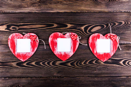 Love card template with blank photo frame heart shaped on the red hearts on wooden backgroundの写真素材