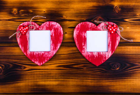 Love card template with blank photo frame heart shaped on the red hearts on wooden backgroundの写真素材