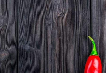 Red chili pepper on the dark wood texture backgroundの写真素材