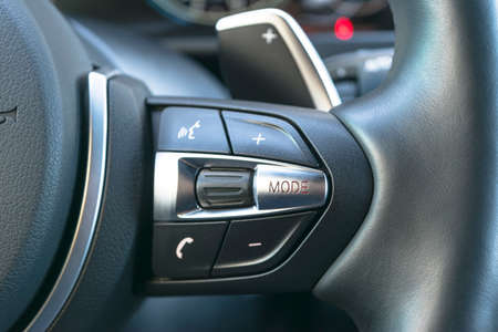 Hands free and media control buttons on the steering wheel in black leather modern car interior