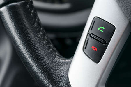 Hands free and media control buttons on the steering wheel in black leather, modern car interior