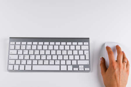 Closeup of businesswoman hand using wireless computer mouse and keyboardの写真素材