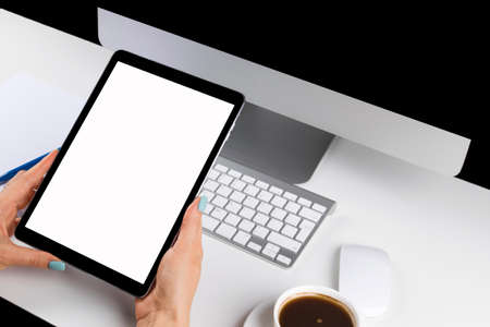 Woman hands holding tablet computer with isolated screen and cup of coffee. Business workplace with...