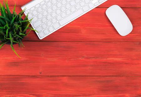 Office desk with copy space. Digital devices wireless keyboard and mouse on red wooden table, top viewの写真素材