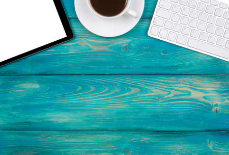 Office desk with copy space. Digital devices wireless keyboard, mouse and tablet computer with empty screen on blue  wooden table with cup of coffee, top viewの写真素材