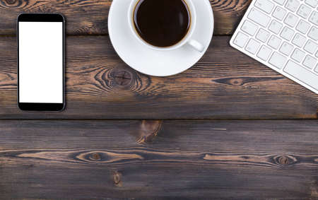 Office desk with copy space. Digital devices wireless keyboard, mouse and tablet computer with empty screen on dark  wooden table with cup of coffee, top viewの写真素材