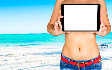 Tablet computer with isolated white screen with empty space for text in hand of a young beautiful girl, ocean backgroundの写真素材