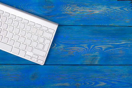Business workplace with computer, wireless keyboard on old blue wooden table background. Office desk with copy spaceの写真素材