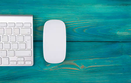 Business workplace with computer, wireless keyboard and mouse on old blue wooden table background. Office desk with copy spaceの写真素材