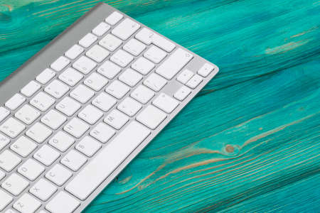 Business workplace with  wireless keyboard on old blue wooden table background. Office desk with...