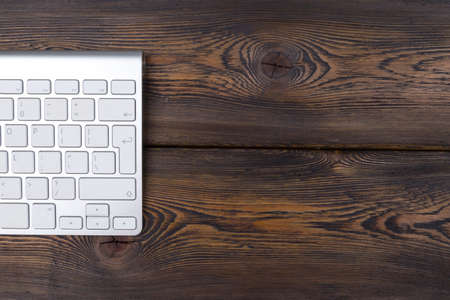 Close up view of a business workplace with wireless computer keyboard, keys on old dark natural...