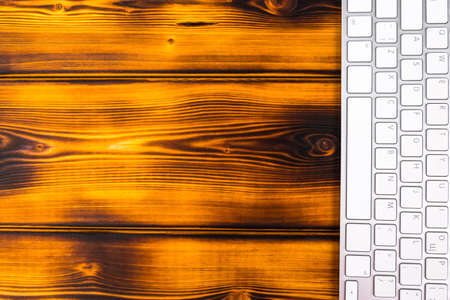 Close up view of a business workplace with wireless computer keyboard, keys on old dark burned...