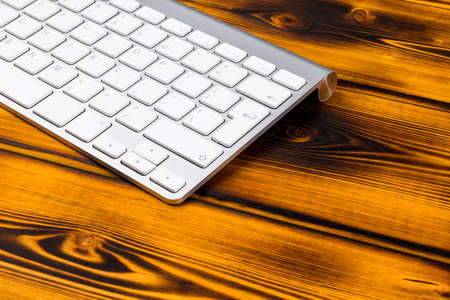 Close up view of a business workplace with wireless computer keyboard, keys on old dark burned...