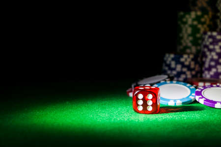 Stack of Poker chips on a green gaming poker table with poker dice at the casino . Playing a game...