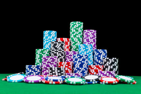 Stack of Poker chips on a green gaming poker table with poker dice at the casino . Playing a game...