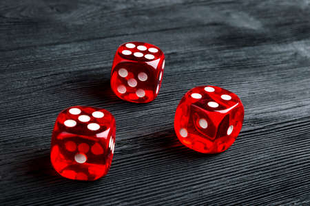 risk concept - playing dice at black wooden background. Playing a game with dice. Red casino dice rolls. Rolling the dice concept for business risk, chance, good luck or gamblingの写真素材