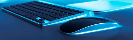 Business workplace with computer wireless keyboard and mouse on old blue table background. Office desk with copy spaceの写真素材