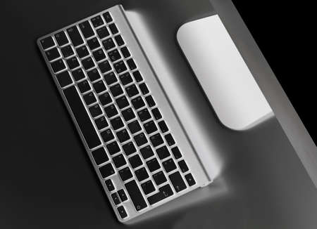 Business workplace with computer wireless keyboard and mouse on old black table background. Office...