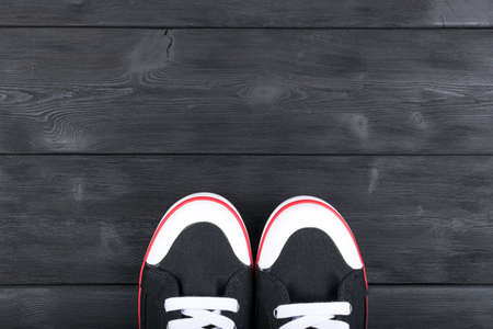 Overhead view of black and white shoes on blackwooden floor. Shoes on a wooden background. Sneakers on a wooden floor. Sport, fitness, shoes, footwear and objects conceptの写真素材