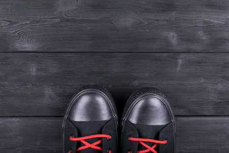Overhead view of black and white shoes on black wooden floor. Shoes on a wooden background. Sneakers on a wooden floor. Sport, fitness, shoes, footwear and objects conceptの写真素材