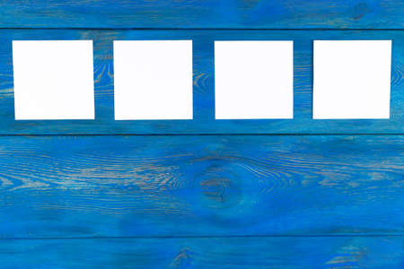 White blank cards on blue wooden table with copy space. Creative reminder, small sheets of paper on desk with empty space for text, light memo background,の写真素材