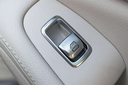 Car white leather interior details of door handle with windows controls and adjustments. Car window controls of modern car.の写真素材