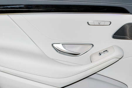 Door handle with Power seat and window contol buttons of a luxury passenger car. White leather interior of the luxury modern car. Modern car interior detailsの写真素材