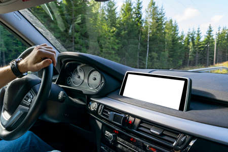 Male hands holding car steering wheel. Hands on steering wheel of a car driving near the lake. Man driving a car inside cabin. Multimedia system isolated white blank screen. Copy spaceの写真素材