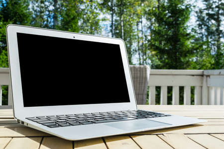 Wooden white office desk table with open blank laptop computer empty space. Front view with copy space. Grey laptop on wooden desk backgroundの写真素材