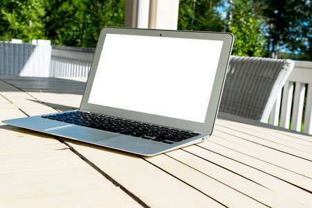 Wooden white office desk table with open blank laptop computer empty space. Front view with copy space. Grey laptop on wooden desk backgroundの写真素材