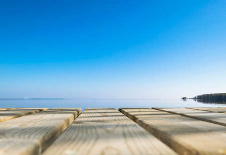 Wooden board empty table in front of blue sea & sky background. Perspective wood floor over sea and sky  beach & summer concepts.の写真素材
