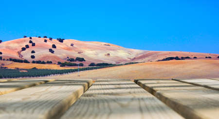 Wooden board empty table in front of blue sky & mountain background. Perspective wood floor over field and mountain & summer concepts.の写真素材
