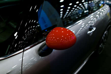 Red Left side Car mirror with reflection of a modern car. Car exterior detailsの写真素材