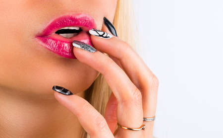 Beautiful Woman Face With Red Lipstick On Plump Full Sexy Lips. Closeup Of Girl's Mouth With hand touching Professional Lip Makeup. Closeup of sensuous woman biting red lipsの写真素材