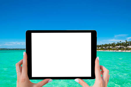 Blank empty tablet computer in the hands of girl on the tropical turquoise ocean beach. Isolated...